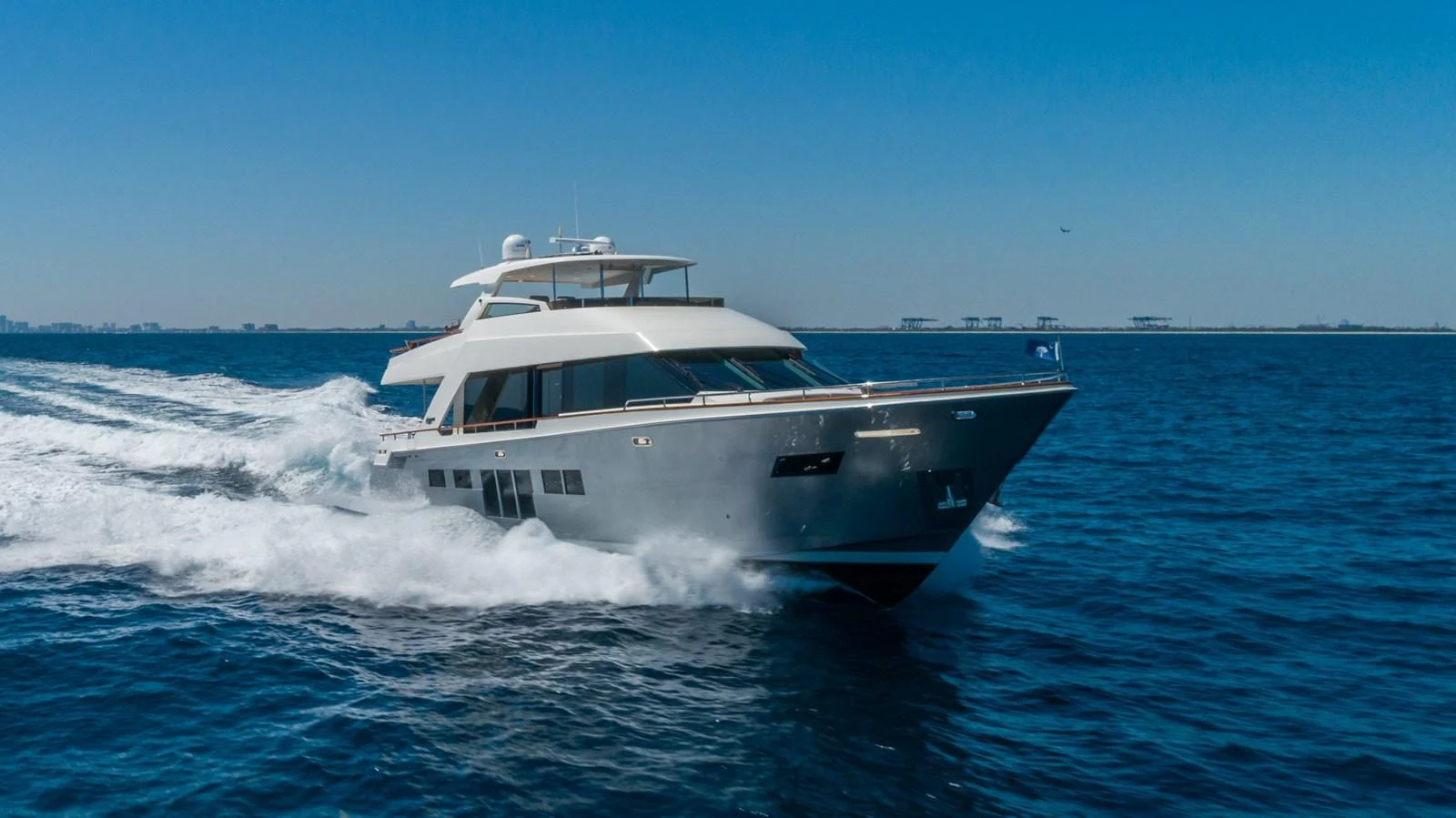 A sleek yacht cruises swiftly across the open sea under a clear blue sky. aboard WHISTLE Yacht for Sale