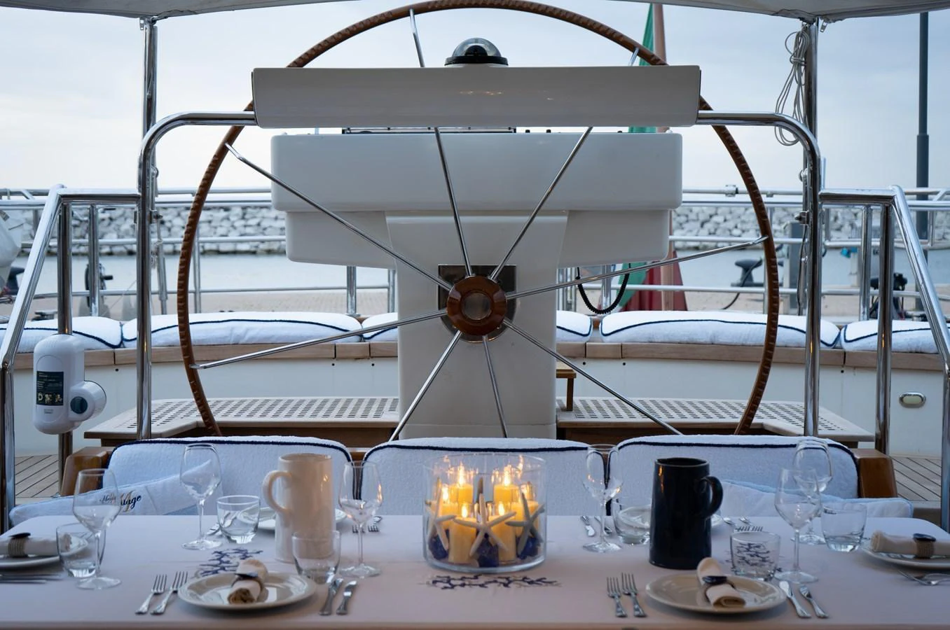 A beautifully set dining table on the yacht's deck, featuring elegant tableware and a centerpiece of candles. aboard HERITAGE M Yacht for Sale