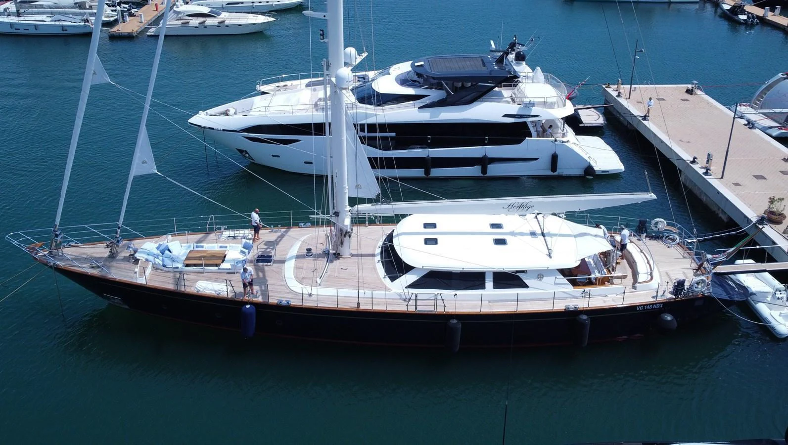 A sleek yacht is docked in a marina, showcasing its elegant design and spacious deck. aboard HERITAGE M Yacht for Sale