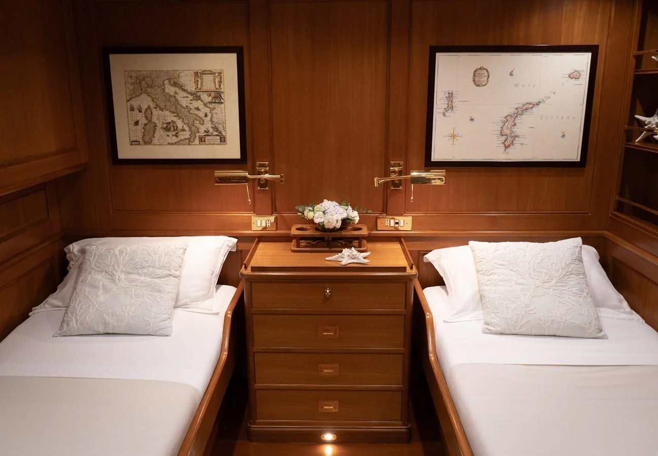 The twin stateroom features elegant wood paneling and comfortable bedding. aboard HERITAGE M Yacht for Sale