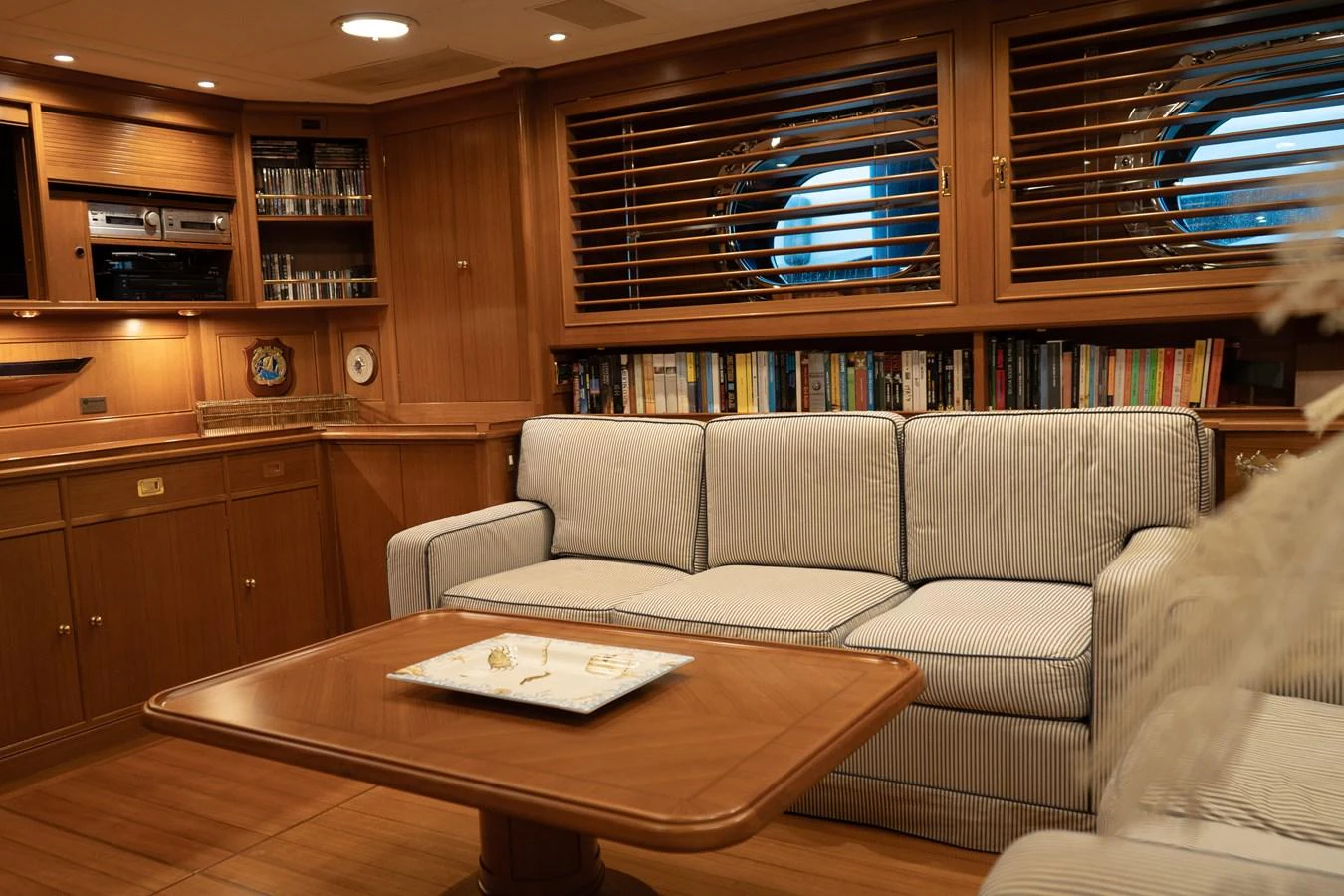 The yacht's salon features a cozy seating area with a plush sofa and a well-stocked bookshelf, creating a warm and inviting atmosphere. aboard HERITAGE M Yacht for Sale