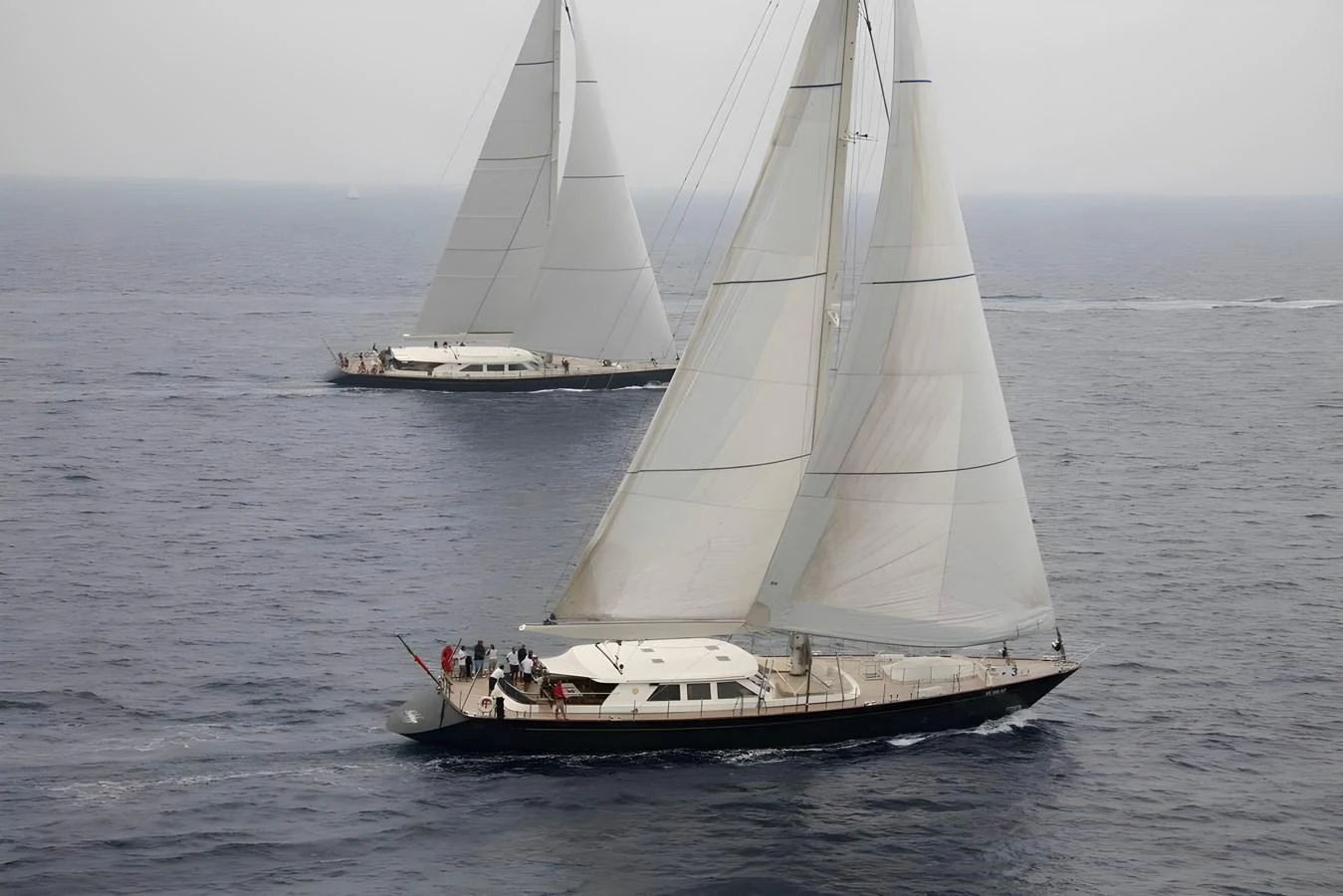 Two elegant sailing yachts glide gracefully across the open sea. aboard HERITAGE M Yacht for Sale