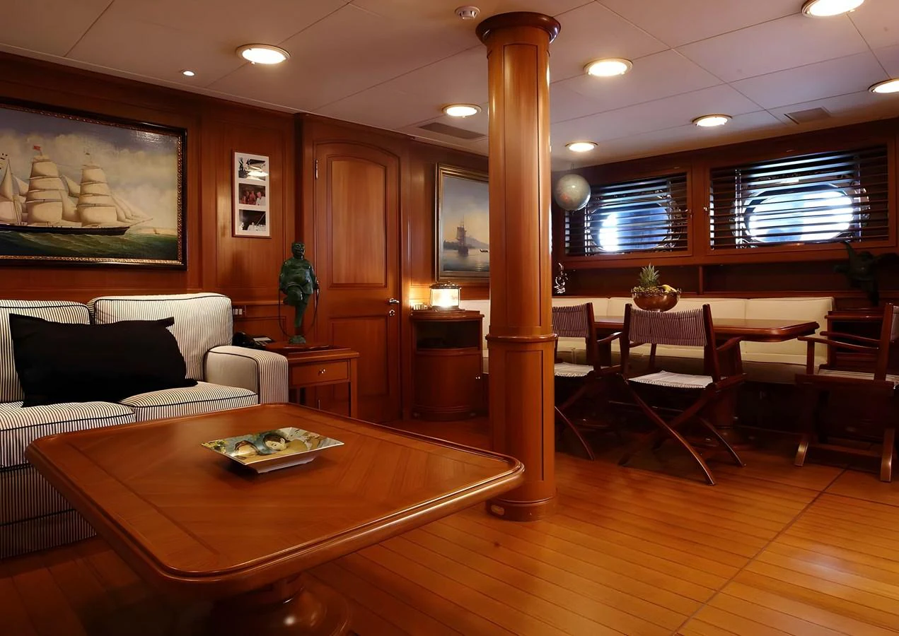 The yacht's interior features a warm and inviting lounge area with wooden accents and comfortable seating. aboard HERITAGE M Yacht for Sale