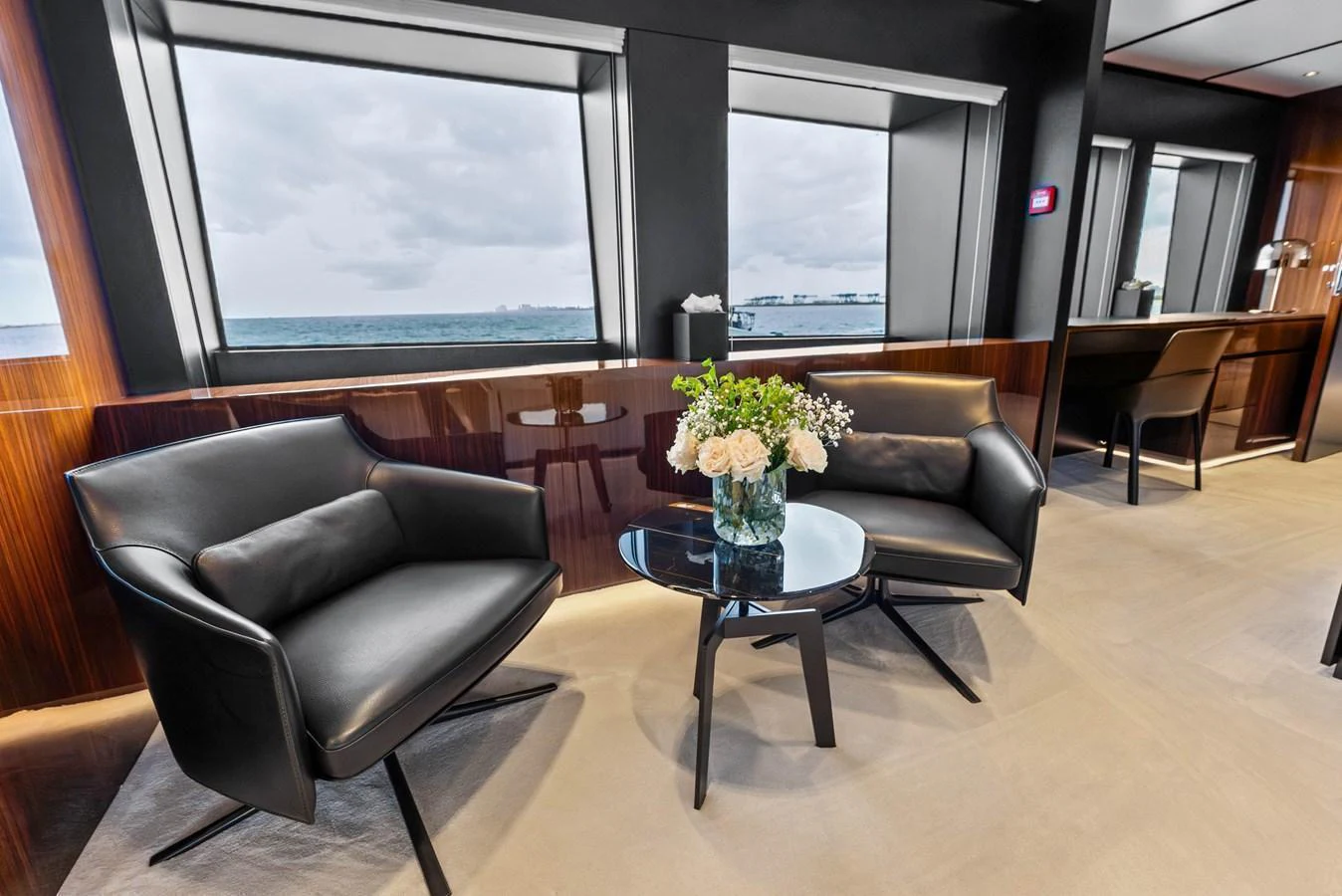 The yacht's interior features a stylish seating area with modern black chairs and a glass table, complemented by large windows offering a sea view. aboard EURO Yacht for Sale