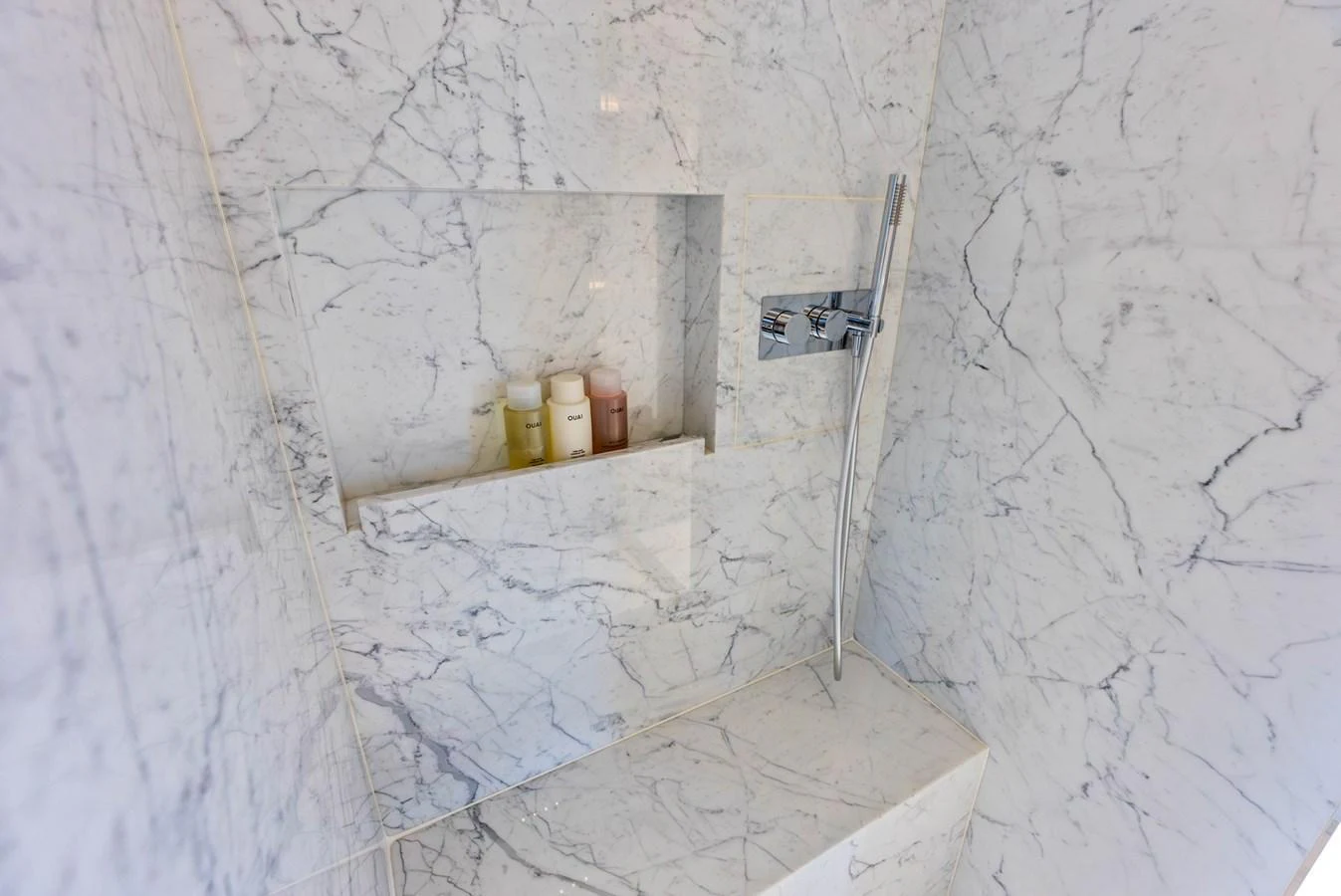 The yacht's bathroom features elegant marble walls and a sleek, modern shower fixture. aboard EURO Yacht for Sale