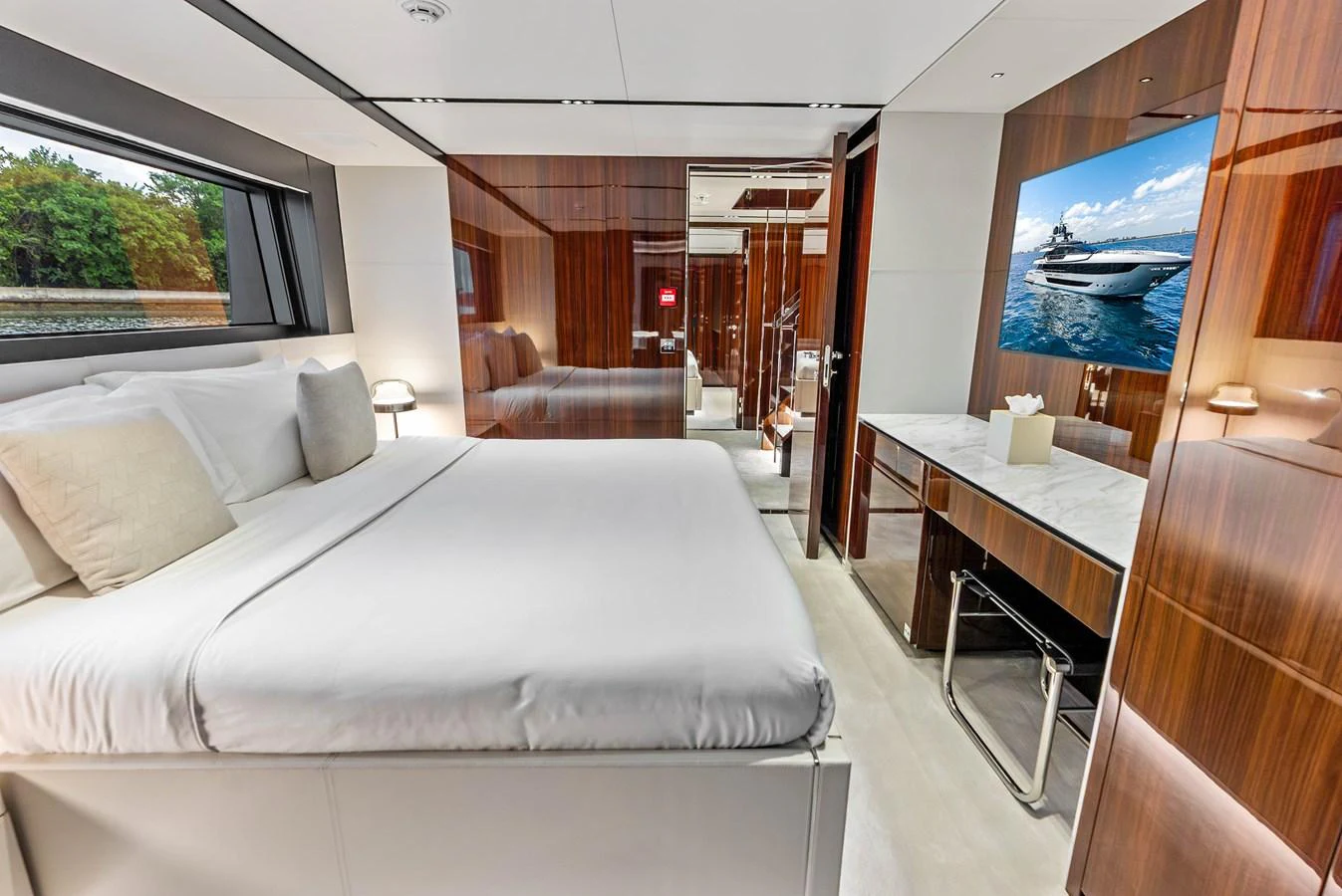 A luxurious stateroom featuring a large bed, sleek wood paneling, and a view of the water. aboard EURO Yacht for Sale