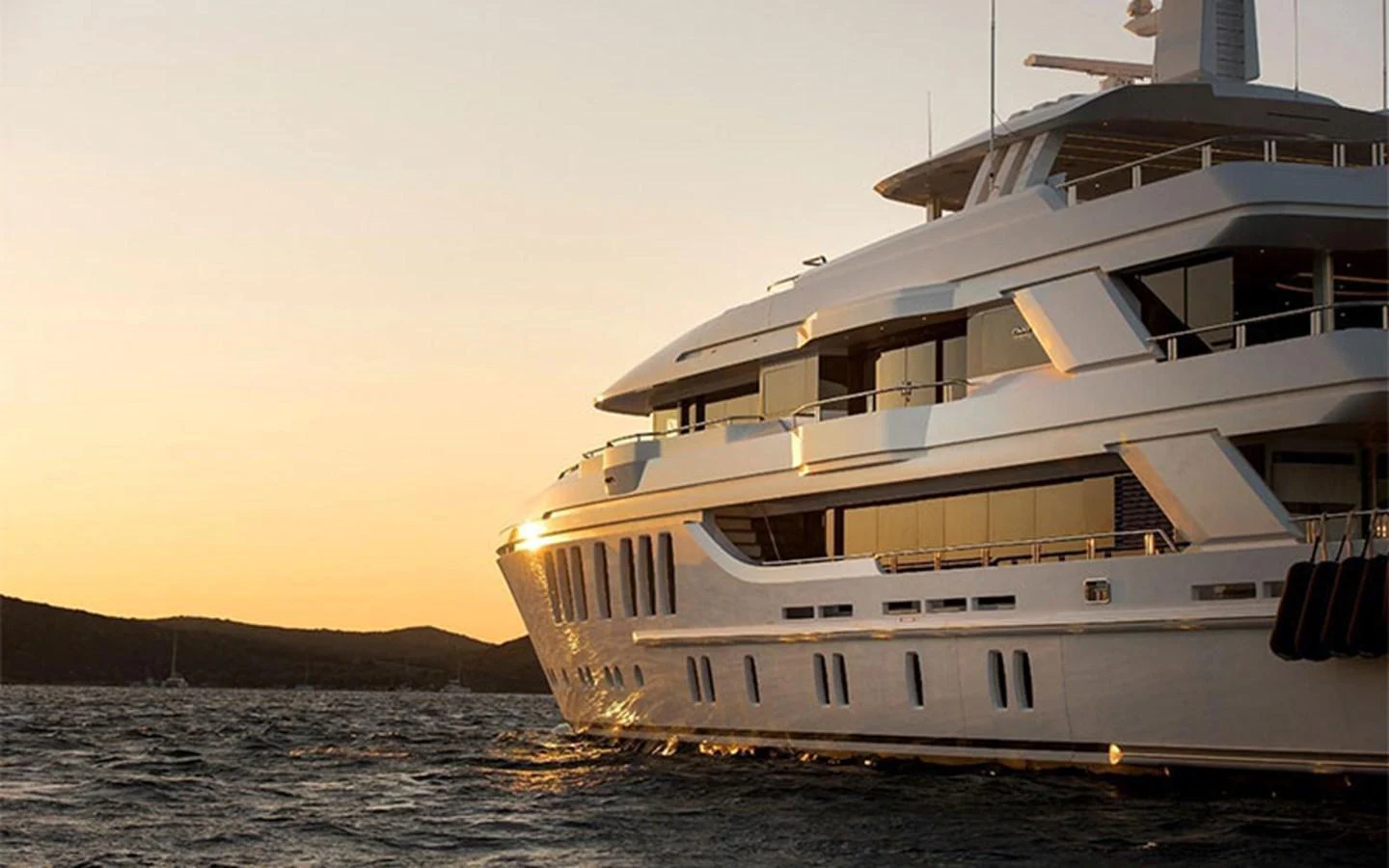 A luxurious yacht glides through the water at sunset, showcasing its sleek design and elegant lines. aboard CMB  108 Yacht for Sale