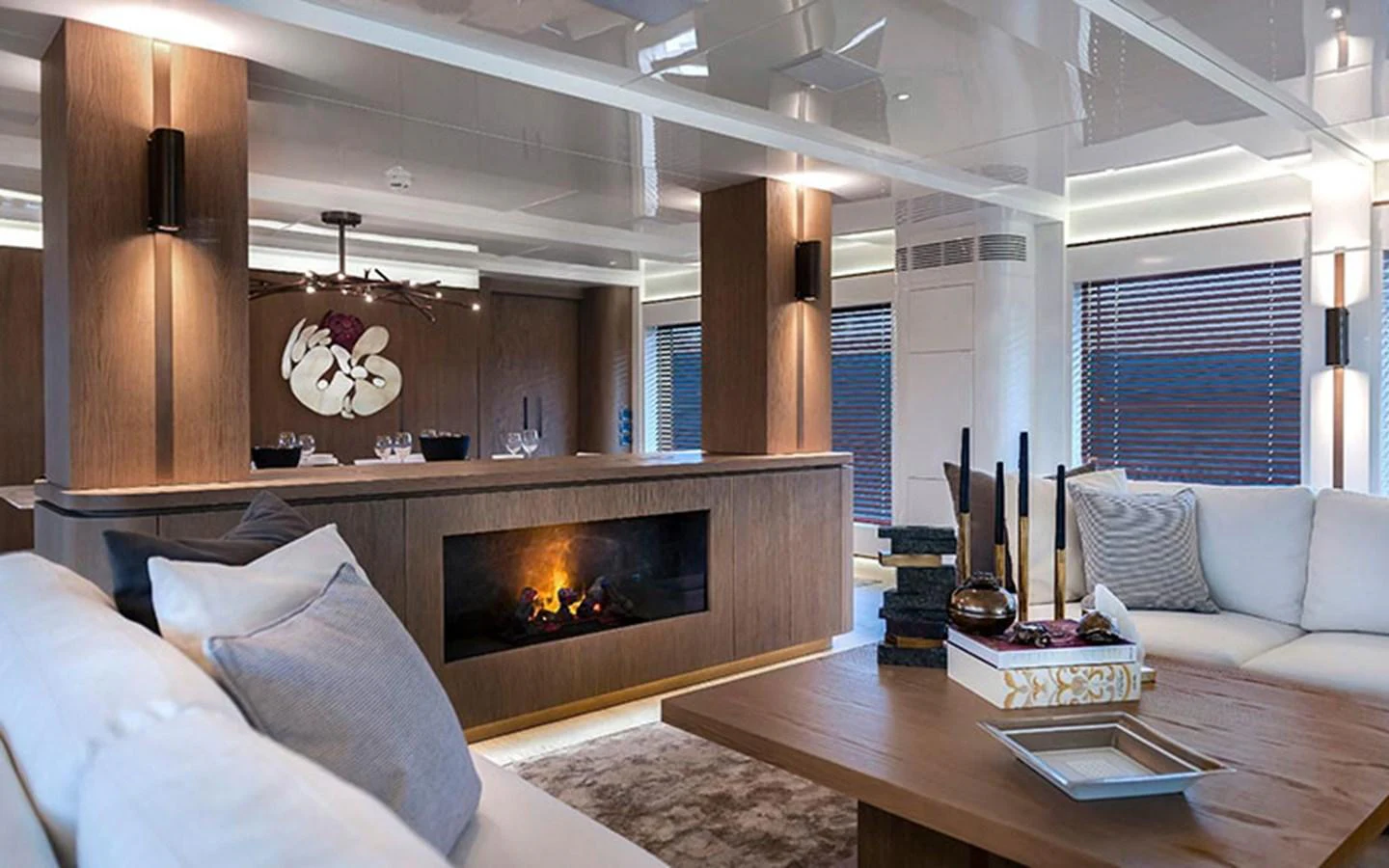 The yacht's salon features a cozy fireplace, modern decor, and ample seating for relaxation. aboard CMB  108 Yacht for Sale