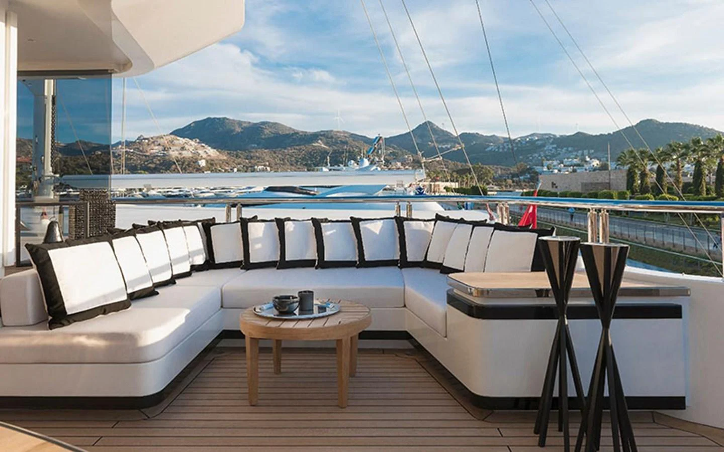 The aft deck features a spacious seating area with a stunning view of the marina and surrounding hills. aboard CMB  108 Yacht for Sale