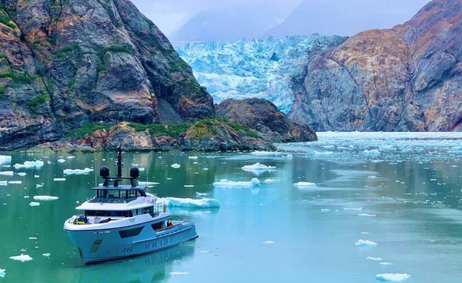 A sleek yacht navigates through icy waters surrounded by majestic cliffs and glaciers. aboard OCEAN DREAMWALKER III Yacht for Sale