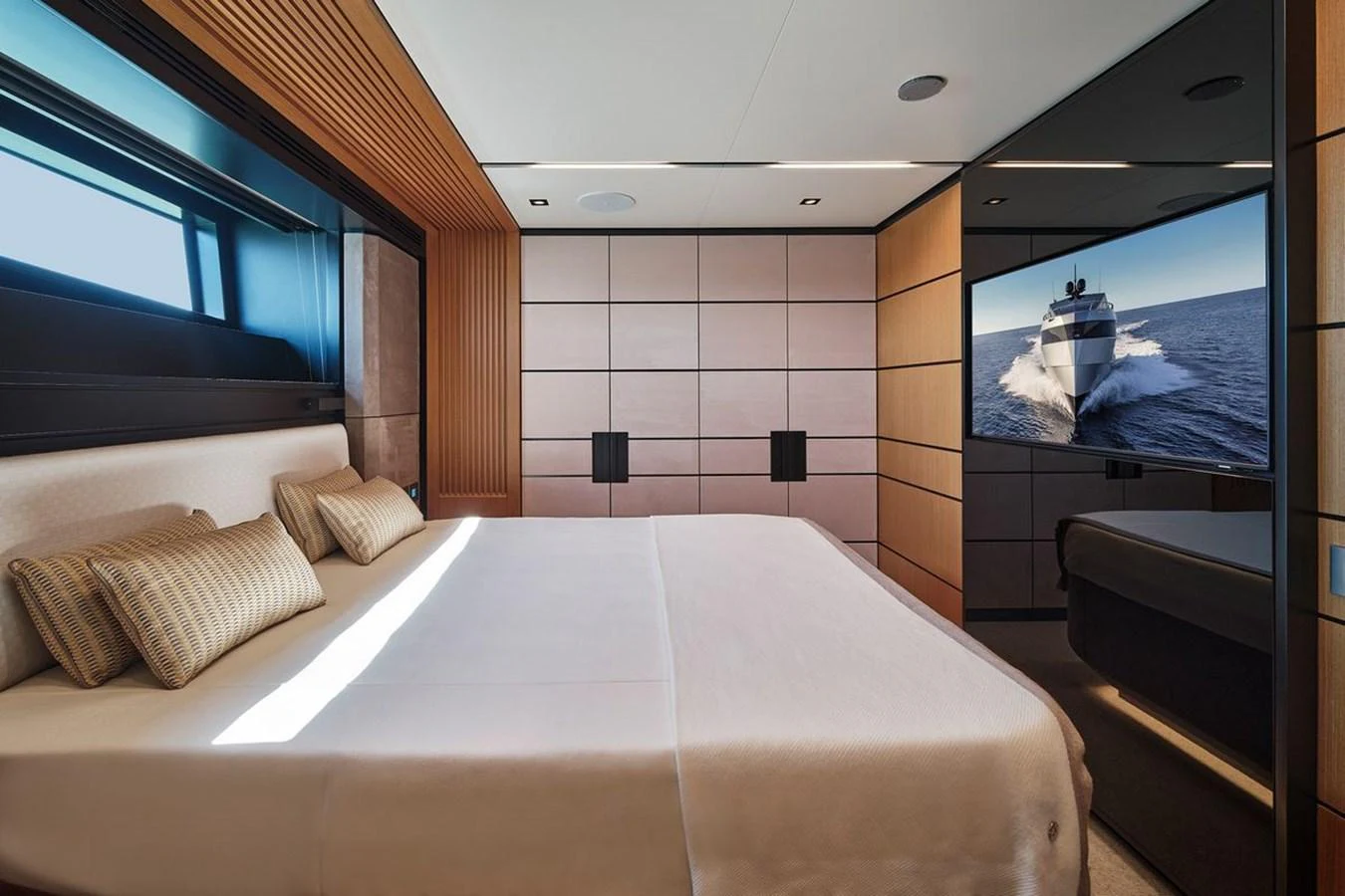 The stateroom features a luxurious bed with modern design elements and a large window offering natural light. aboard CARAT Yacht for Sale