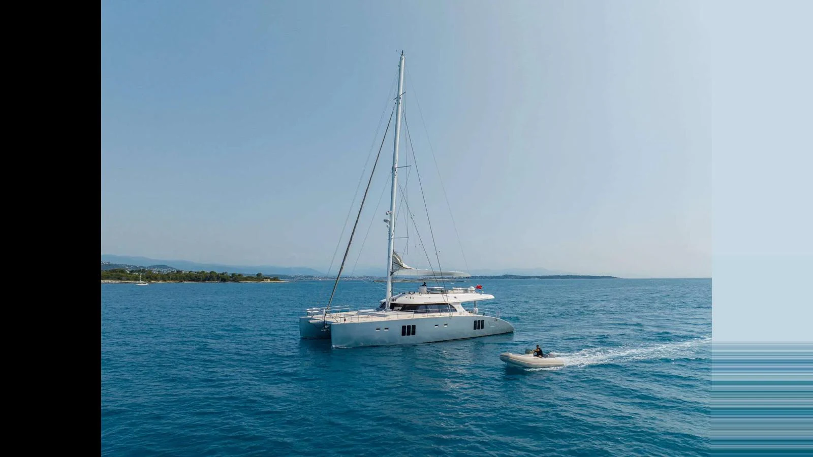 A sleek yacht sails gracefully on calm waters, accompanied by a small tender. aboard SEAZEN II Yacht for Sale