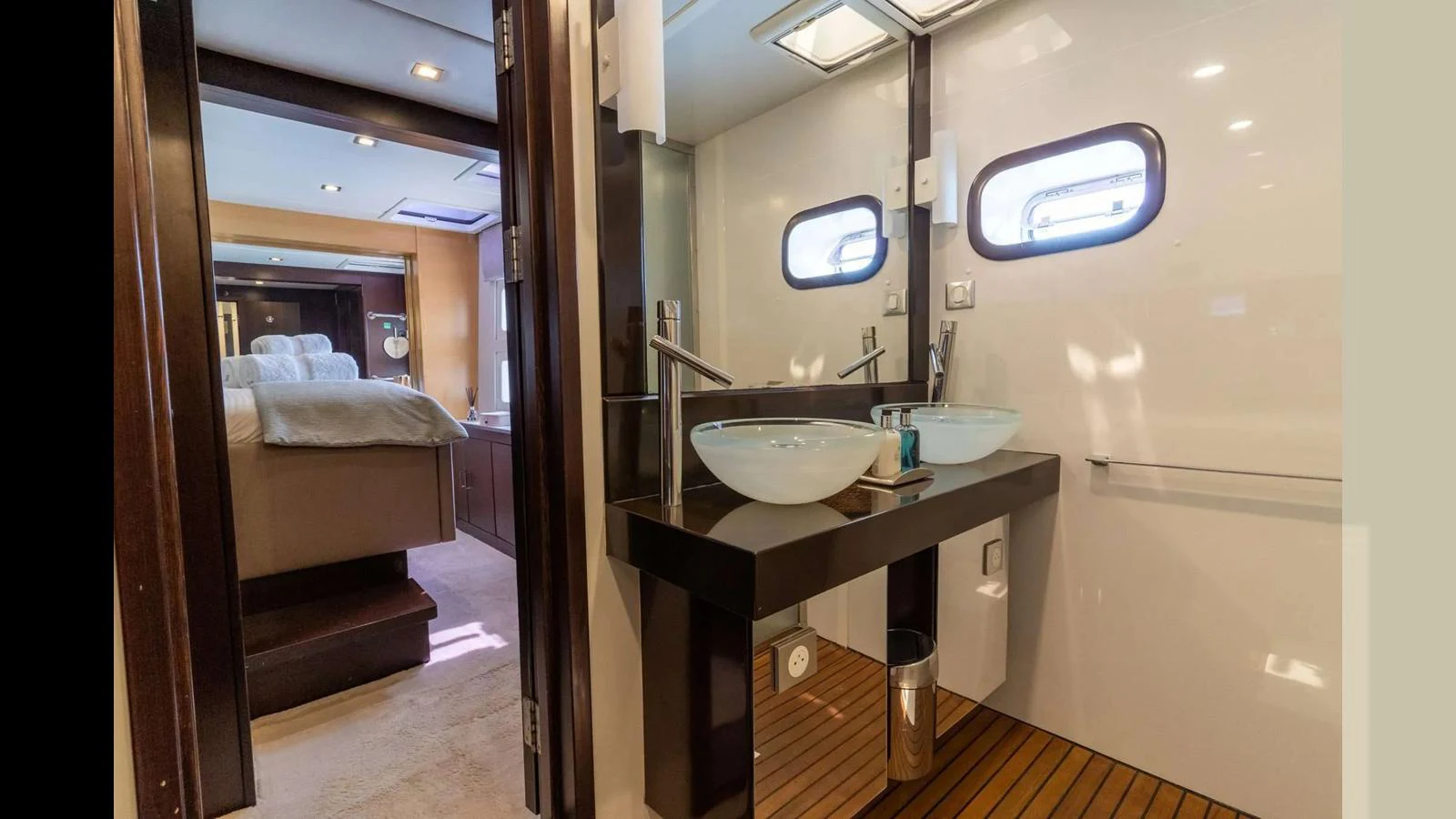 The image showcases a luxurious yacht bathroom with a view into the adjacent stateroom. aboard SEAZEN II Yacht for Sale
