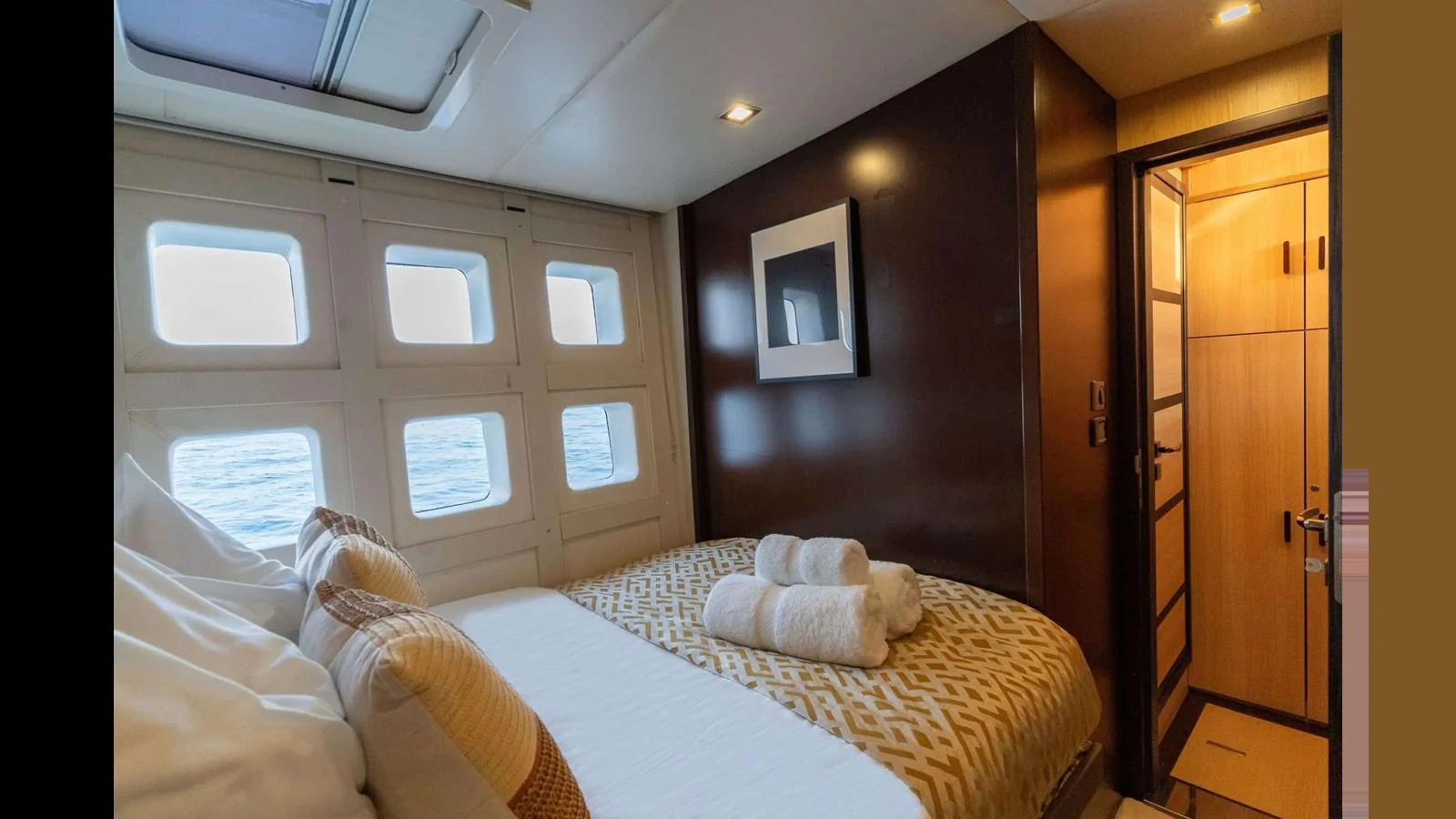 A cozy stateroom with a large bed, soft lighting, and a view of the sea through multiple windows. aboard SEAZEN II Yacht for Sale