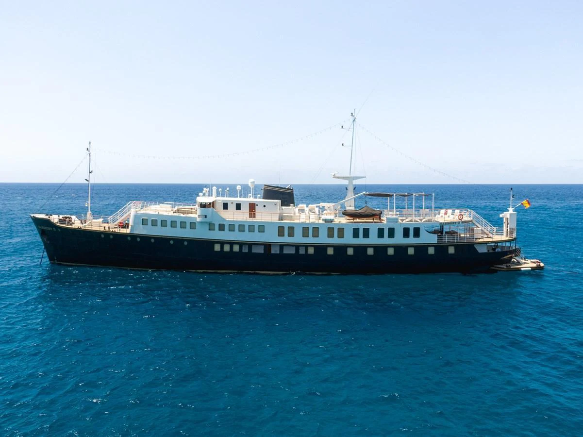 A classic yacht with a sleek profile cruising on calm blue waters. aboard HARMONY II Yacht for Sale