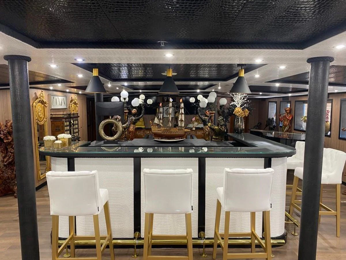 A luxurious yacht interior featuring an elegant bar area with white bar stools and sophisticated decor. aboard HARMONY II Yacht for Sale