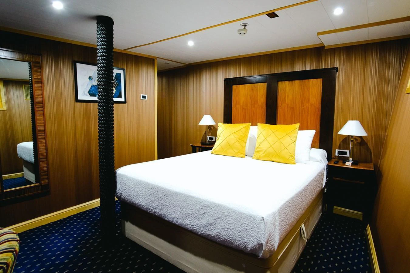 The guest stateroom features a comfortable bed with elegant wood paneling and modern lighting. aboard HARMONY II Yacht for Sale