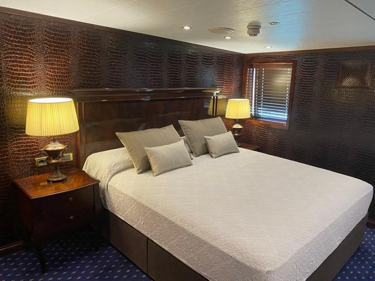 The stateroom features a luxurious bed with elegant lighting and rich wood accents. aboard HARMONY II Yacht for Sale