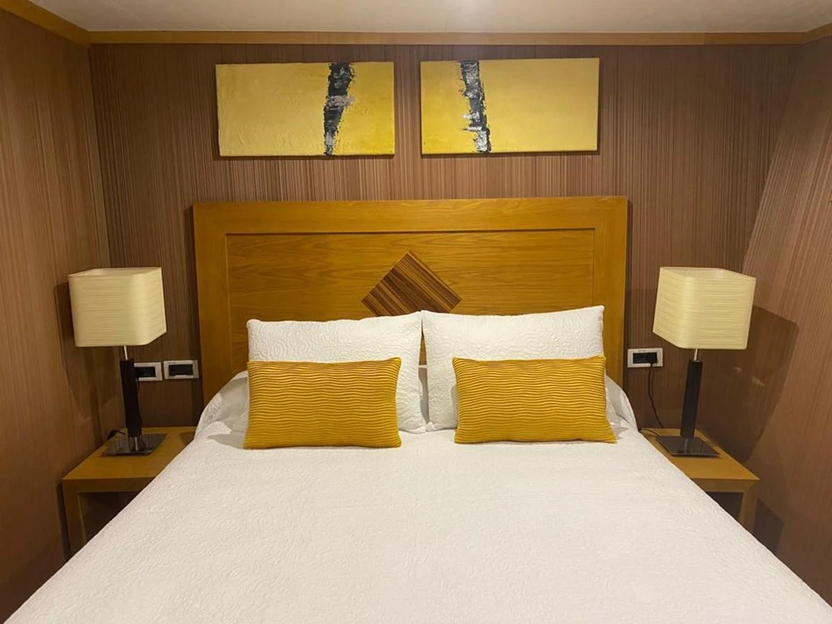 The stateroom features a cozy bed with elegant decor and warm lighting. aboard HARMONY II Yacht for Sale