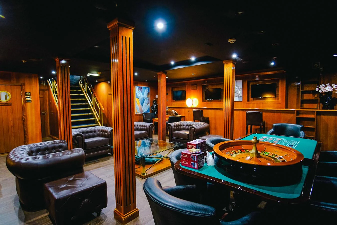 The yacht's casino room offers a luxurious and entertaining space with plush seating and a gaming table. aboard HARMONY II Yacht for Sale