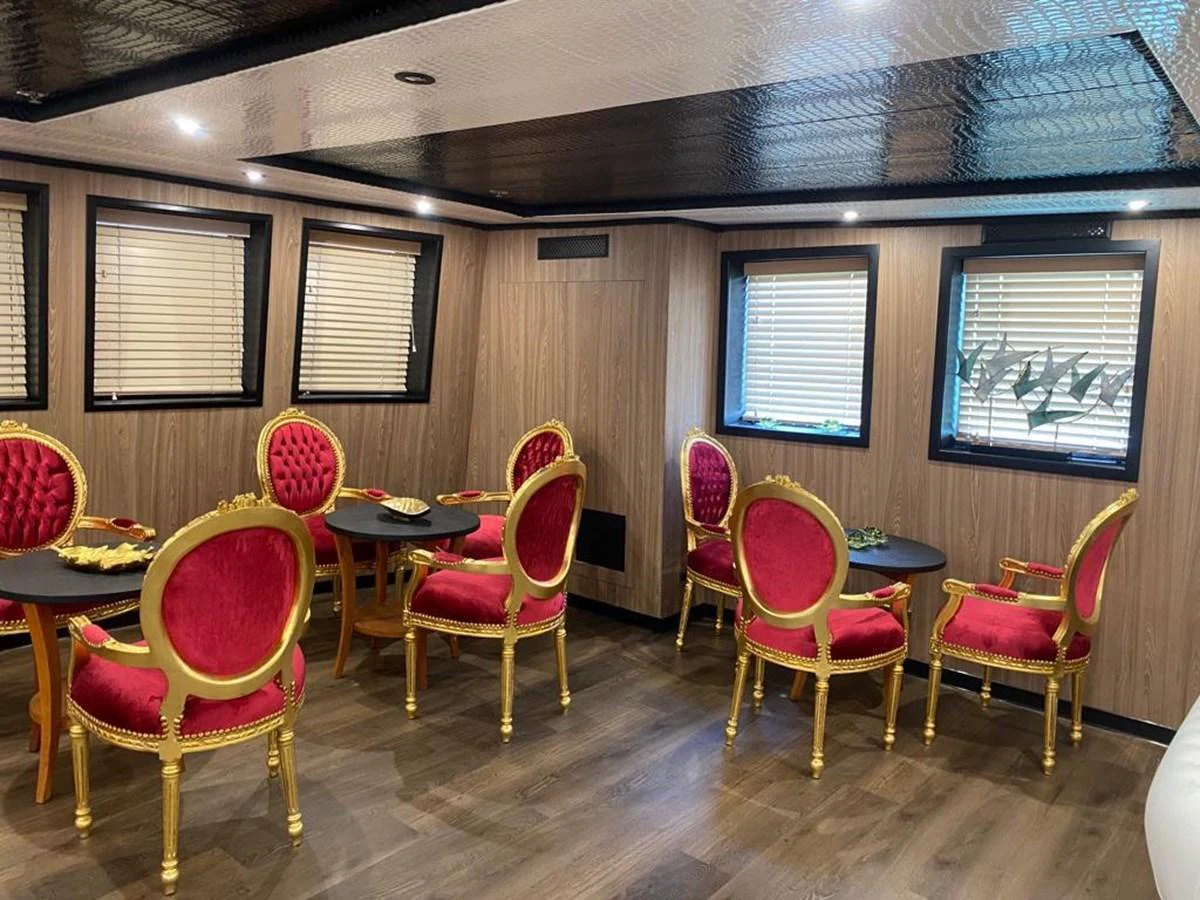 The yacht's dining area features elegant red and gold chairs with round tables, creating a luxurious and inviting atmosphere. aboard HARMONY II Yacht for Sale