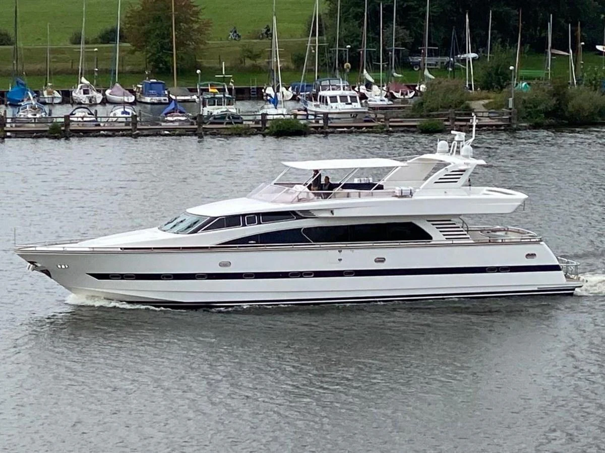 A sleek and modern yacht glides gracefully on the water with a marina in the background. aboard HORIZON ELEGANCE 82 S Yacht for Sale