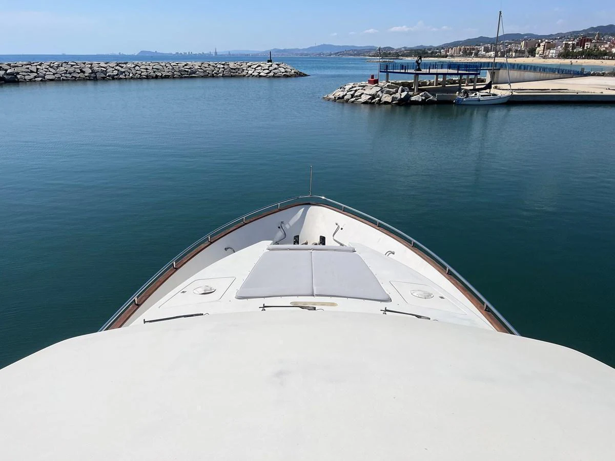 The yacht is docked in a serene marina, offering a peaceful view of the water and distant shore. aboard HORIZON ELEGANCE 82 S Yacht for Sale