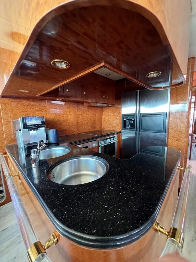 The yacht's galley features sleek black countertops, stainless steel appliances, and rich wooden cabinetry. aboard HORIZON ELEGANCE 82 S Yacht for Sale