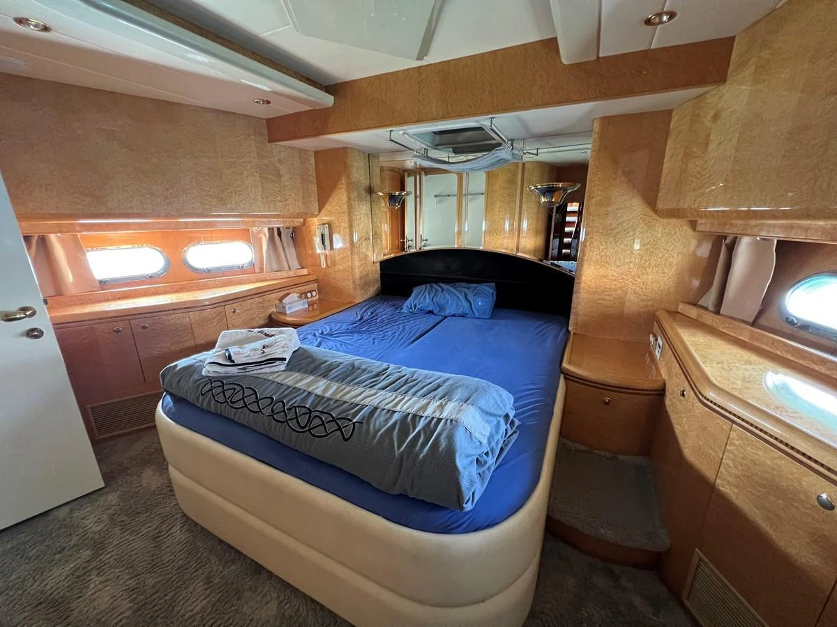 A luxurious stateroom featuring a comfortable bed with blue bedding and ample natural light from the windows. aboard HORIZON ELEGANCE 82 S Yacht for Sale