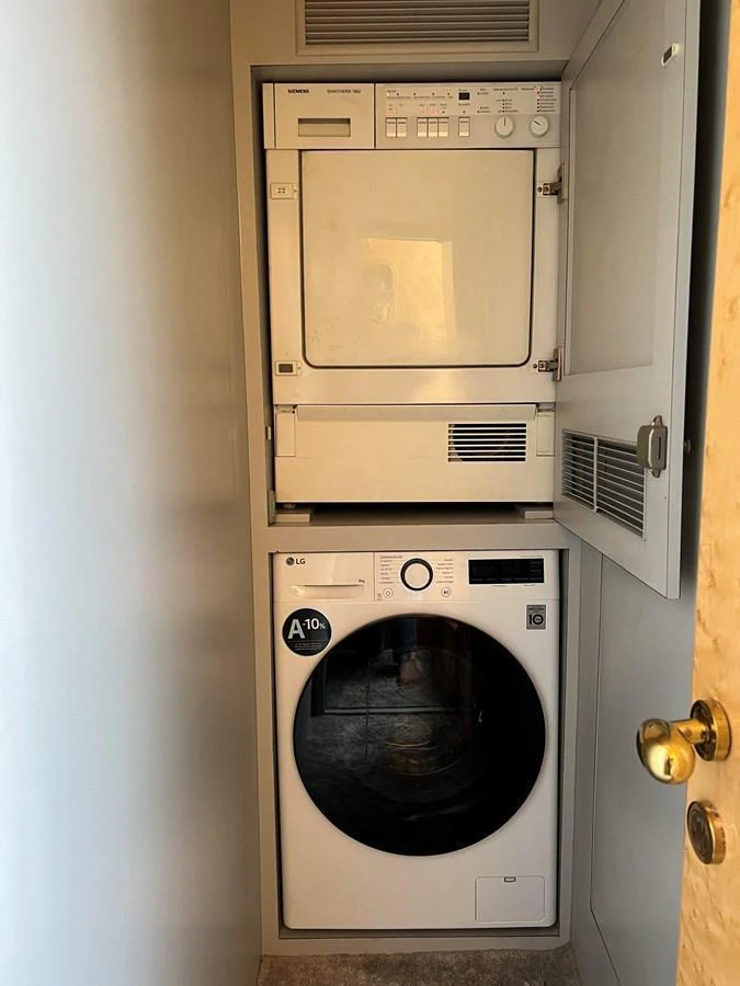 The yacht features a compact and efficient laundry area with a stacked washer and dryer. aboard HORIZON ELEGANCE 82 S Yacht for Sale