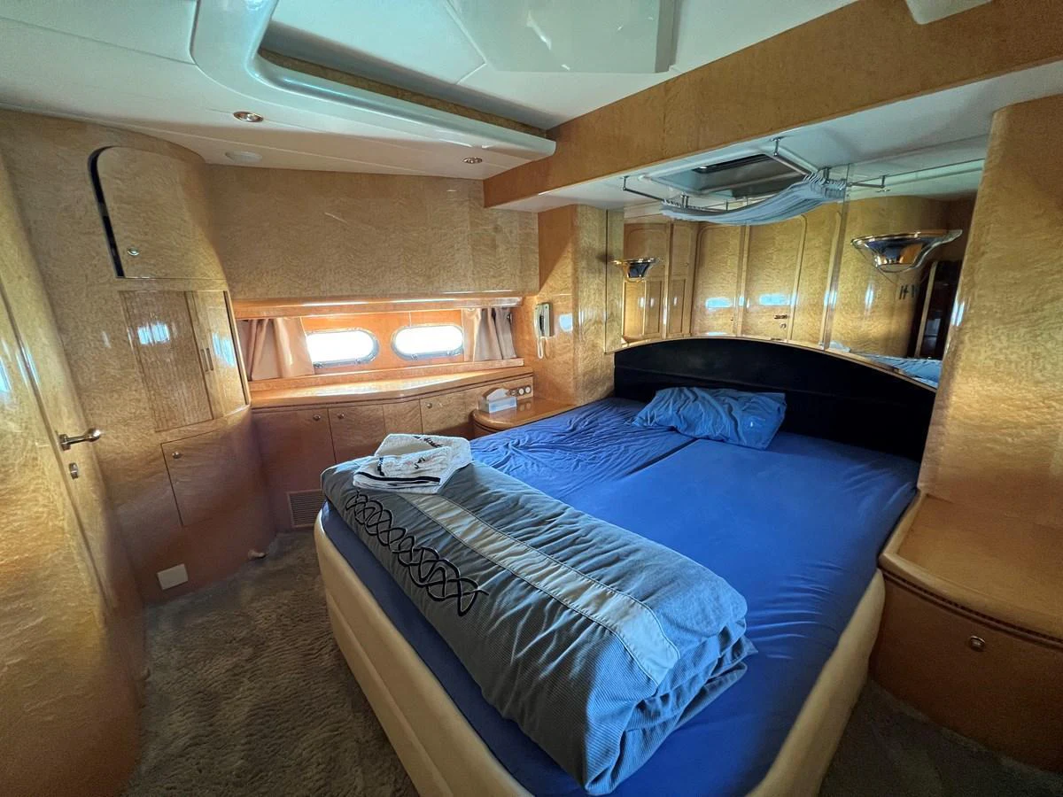 The master stateroom features a comfortable bed with blue bedding and ample natural light from the windows. aboard HORIZON ELEGANCE 82 S Yacht for Sale
