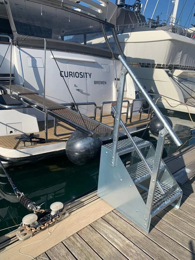 A close-up view of the boarding stairs and docked yacht named 'Curiosity'. aboard HORIZON ELEGANCE 82 S Yacht for Sale