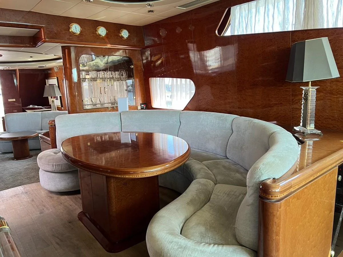 The salon features a cozy curved sofa and a polished wooden table, creating an inviting space for relaxation. aboard HORIZON ELEGANCE 82 S Yacht for Sale