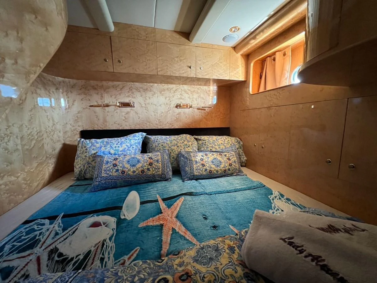 A cozy stateroom featuring a comfortable bed with decorative pillows and a marine-themed bedspread. aboard HORIZON ELEGANCE 82 S Yacht for Sale