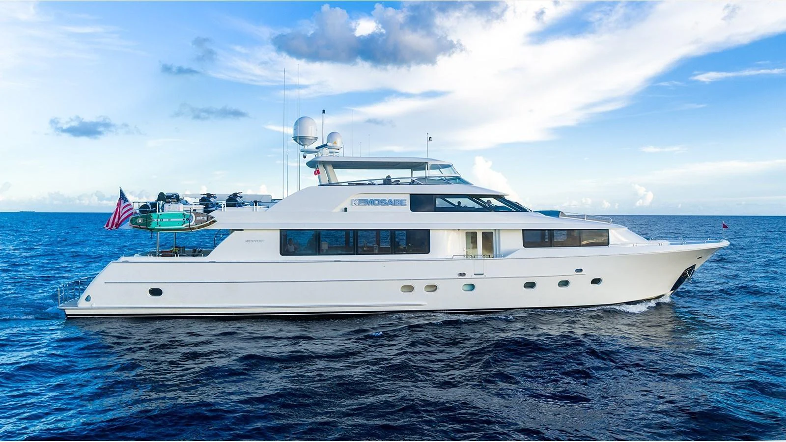 A luxurious yacht cruising on the open sea under a clear blue sky. aboard KEMOSABE Yacht for Sale