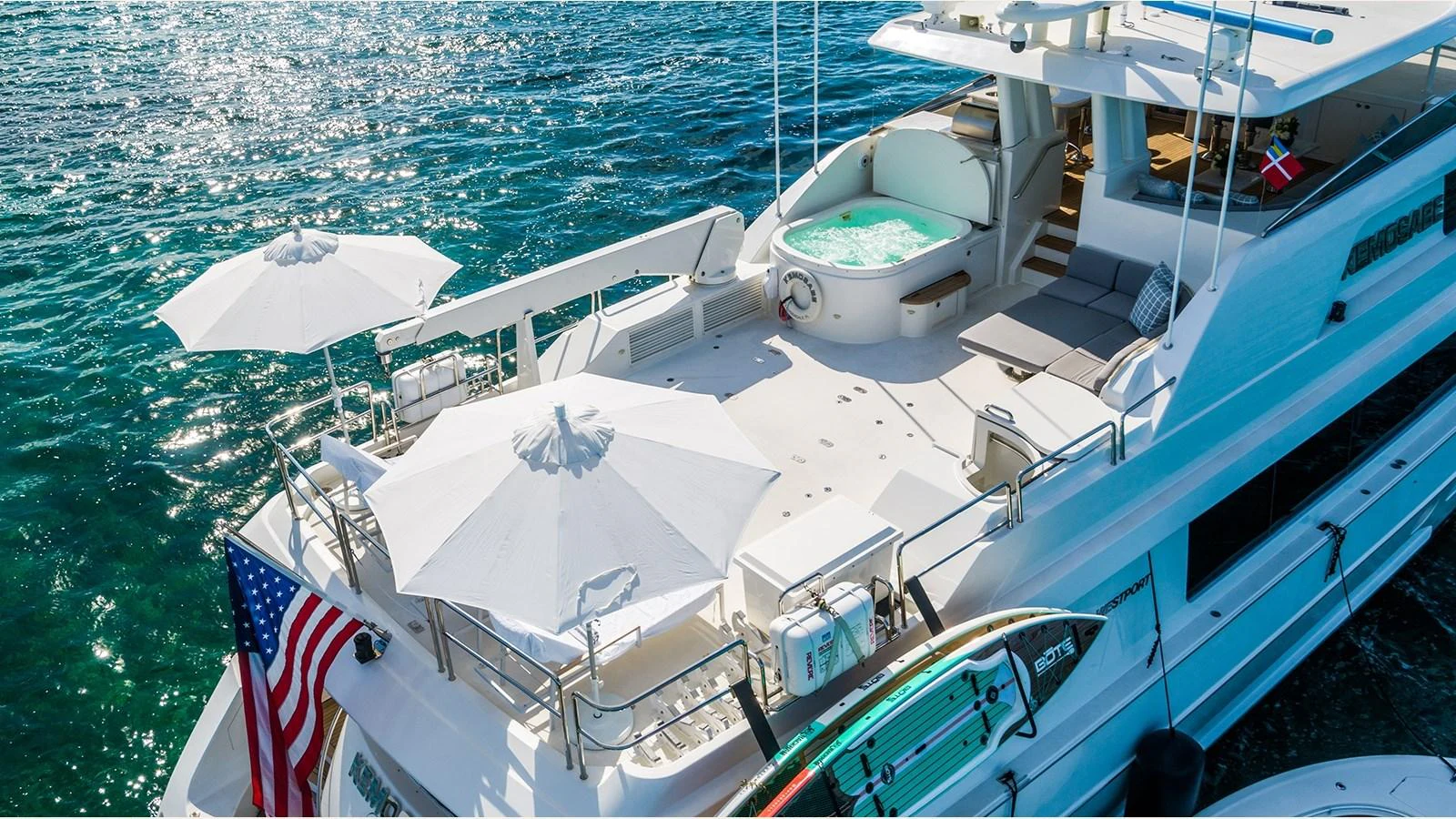 The yacht's sundeck features a jacuzzi, sun loungers, and umbrellas, offering a luxurious space for relaxation. aboard KEMOSABE Yacht for Sale