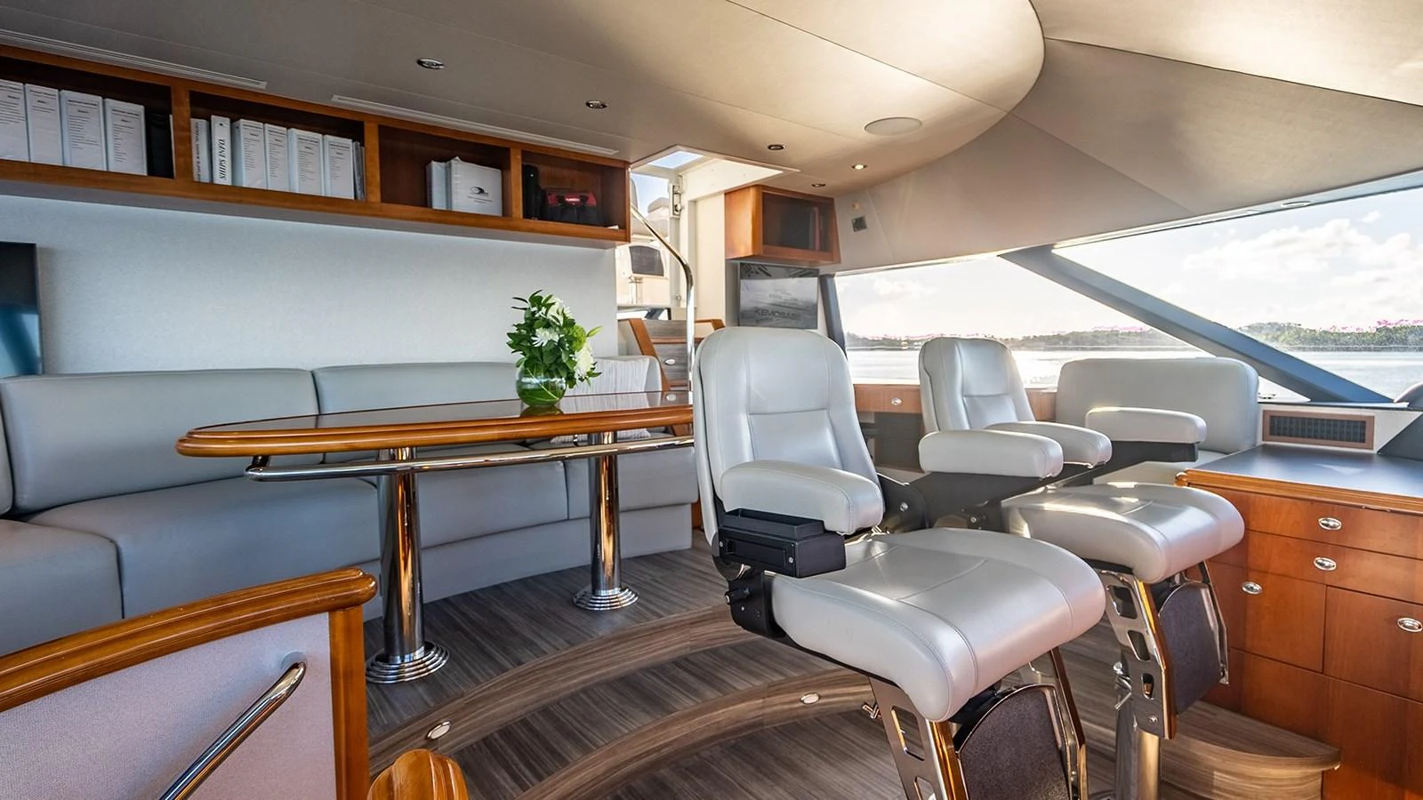 The yacht's helm features plush seating and a sleek, modern design with expansive windows offering a panoramic view. aboard KEMOSABE Yacht for Sale