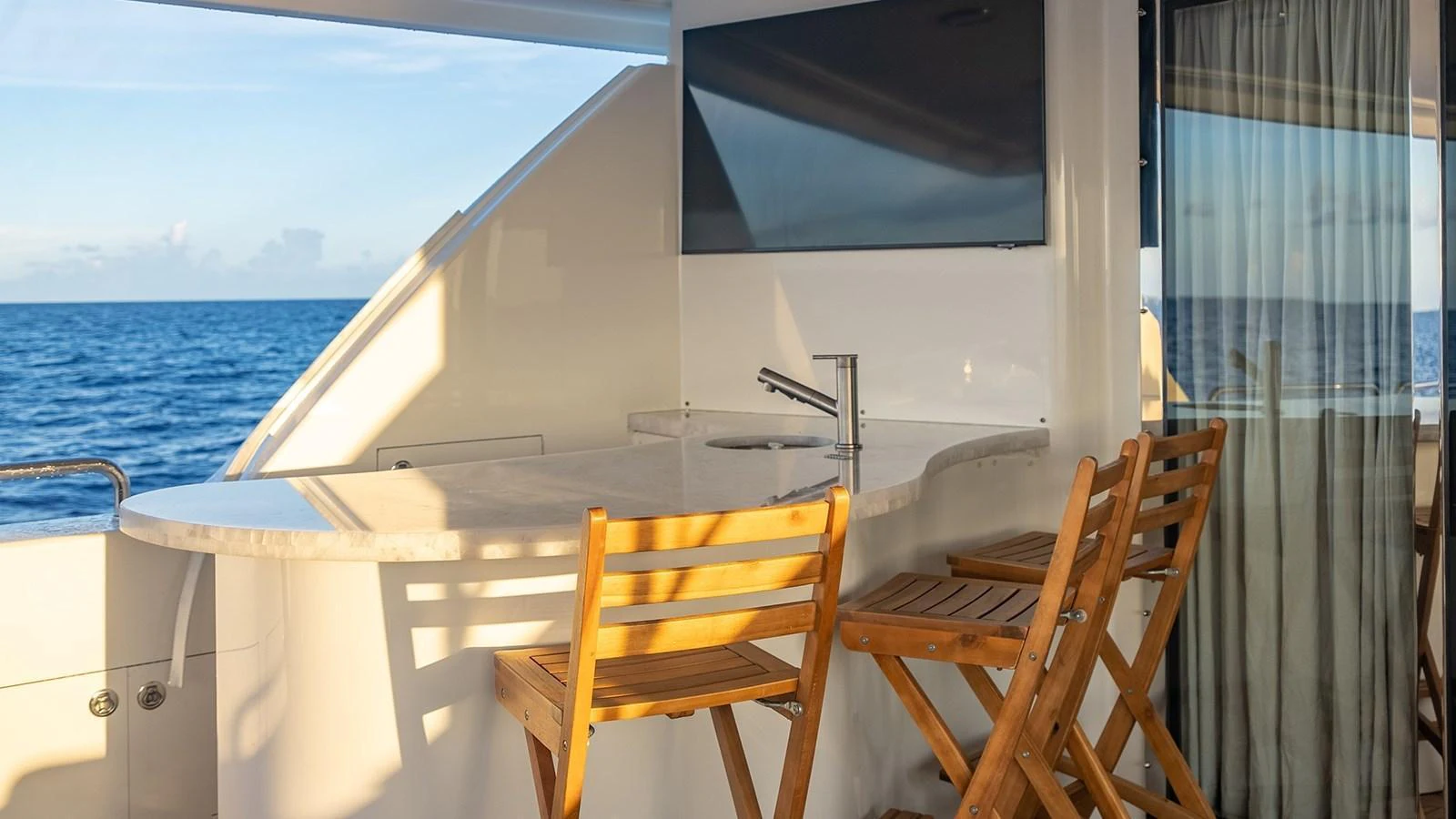 An inviting outdoor bar area with wooden stools and a sleek countertop, perfect for enjoying ocean views. aboard KEMOSABE Yacht for Sale