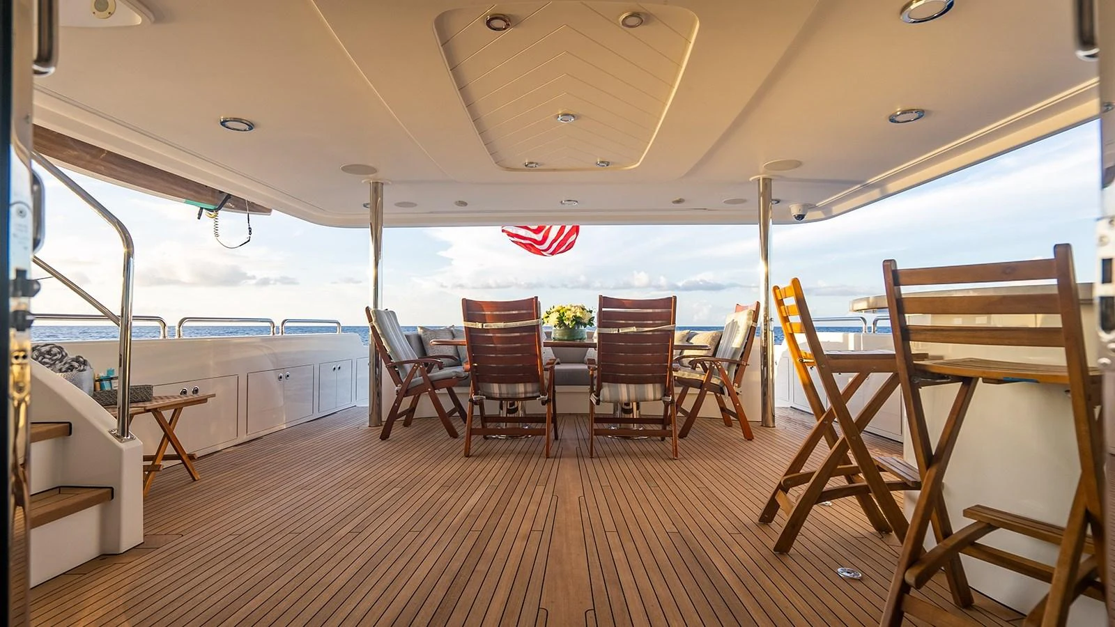 The aft deck features a spacious seating area with wooden chairs and a table, perfect for outdoor dining and relaxation. aboard KEMOSABE Yacht for Sale