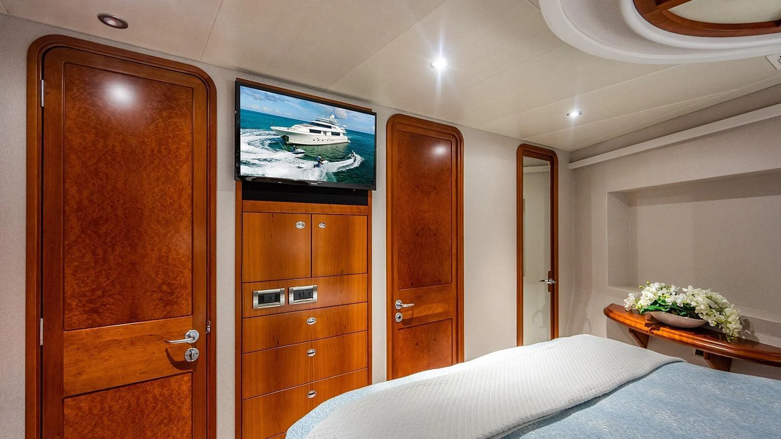 The stateroom features elegant wood finishes, a mounted TV, and a comfortable bed. aboard KEMOSABE Yacht for Sale