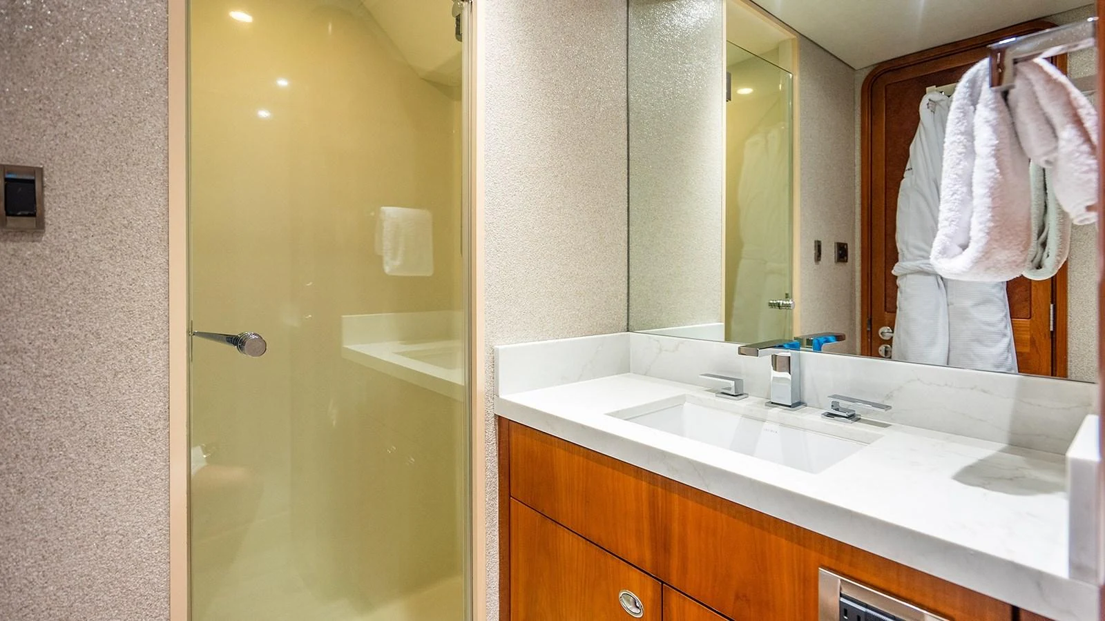 The yacht's bathroom features a sleek design with a modern sink and a glass-enclosed shower. aboard KEMOSABE Yacht for Sale