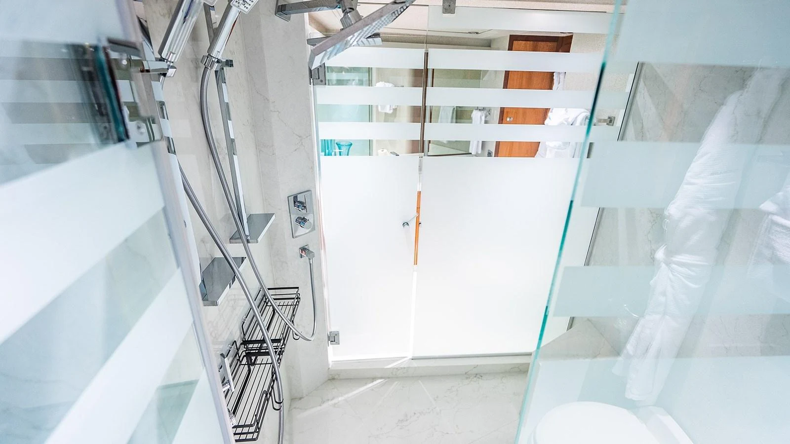 A modern yacht bathroom with frosted glass doors and sleek fixtures. aboard KEMOSABE Yacht for Sale