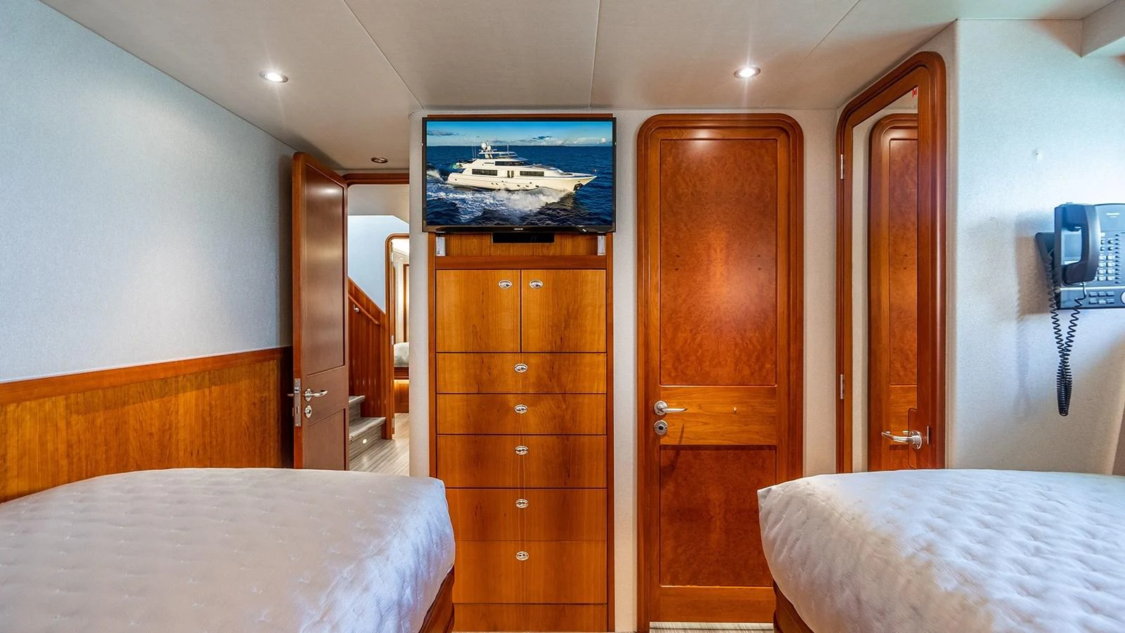 The guest cabin features twin beds, warm wood finishes, and a mounted TV for entertainment. aboard KEMOSABE Yacht for Sale