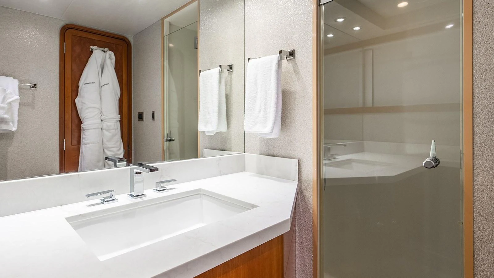 A pristine yacht bathroom featuring a sleek vanity and a glass-enclosed shower. aboard KEMOSABE Yacht for Sale
