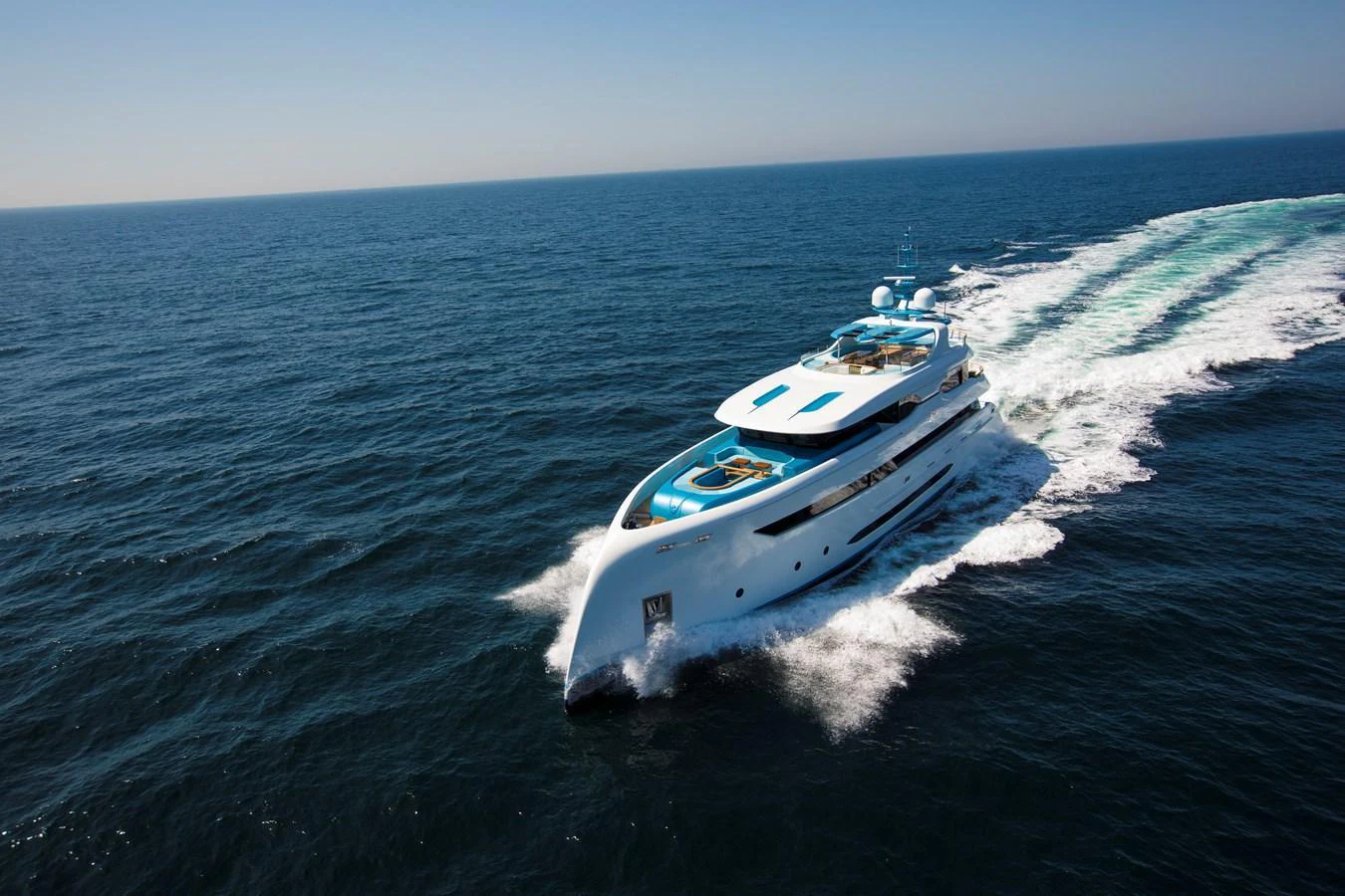 A sleek yacht cruises swiftly across the open sea under a clear blue sky. aboard ELADA Yacht for Sale