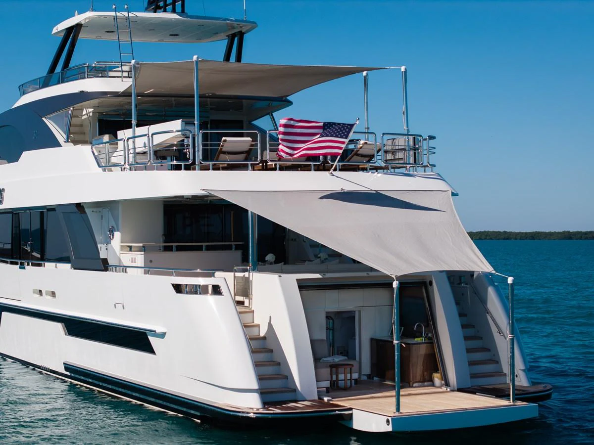 The yacht's aft deck features a shaded lounging area with an American flag waving in the breeze. aboard OCEAN ALEXANDER 37L/01 Yacht for Sale
