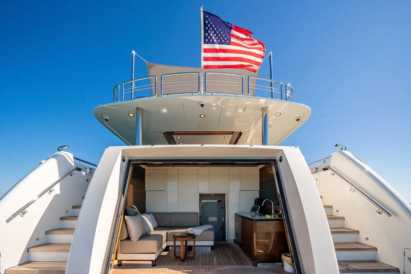 The aft deck features a comfortable seating area with a kitchenette, under a clear blue sky. aboard OCEAN ALEXANDER 37L/01 Yacht for Sale