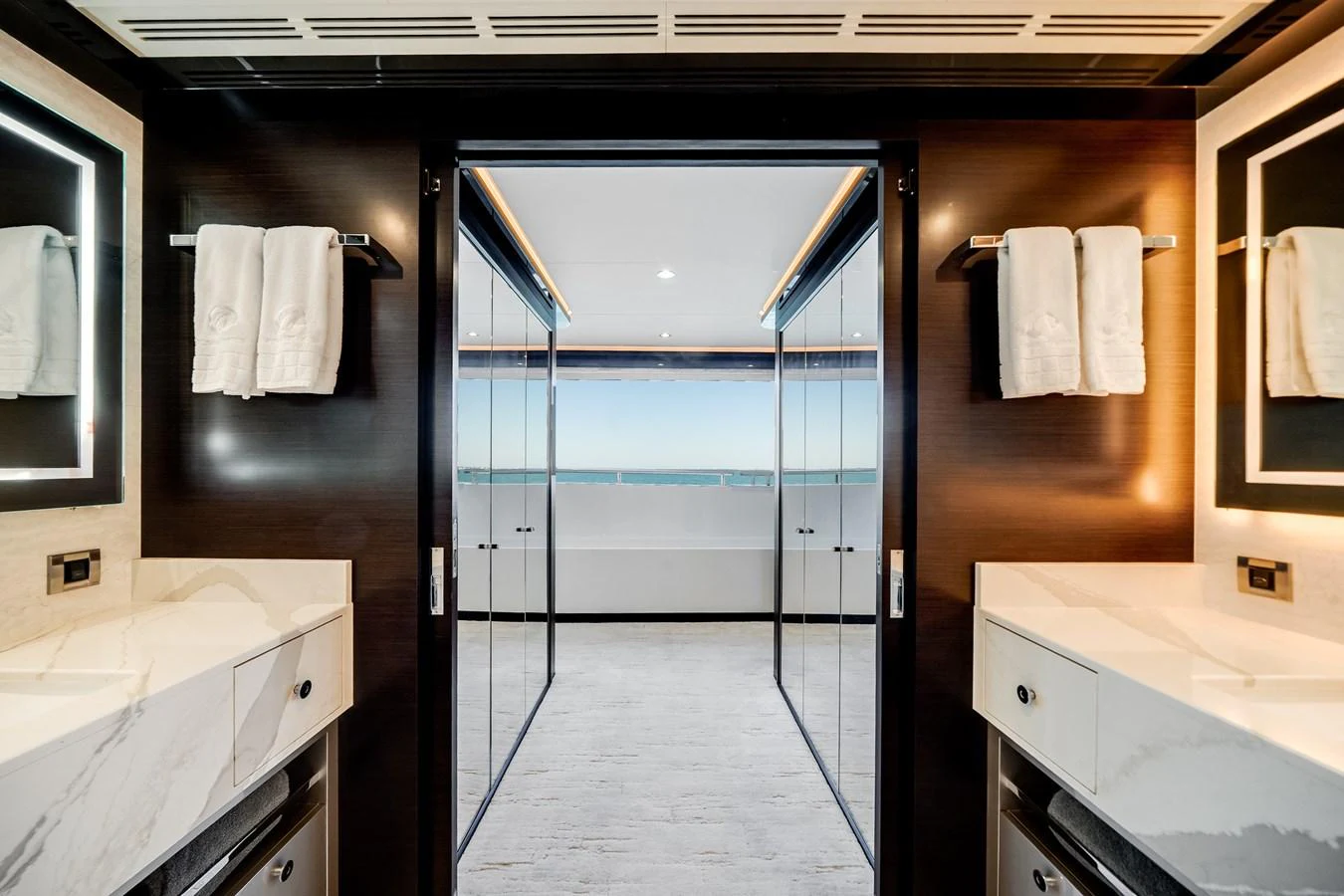 A luxurious yacht bathroom with dual sinks and a view of the ocean through glass doors. aboard OCEAN ALEXANDER 37L/01 Yacht for Sale