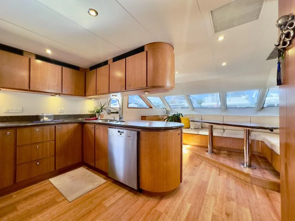 The yacht's galley features modern wooden cabinetry, a sleek countertop, and a cozy dining area with large windows. aboard BREAKAWAY Yacht for Sale
