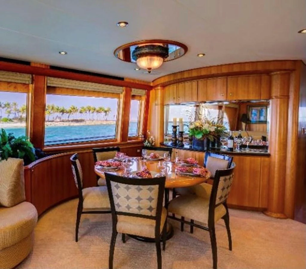 The elegant dining area features a round table with seating for four, surrounded by large windows offering stunning ocean views. aboard BREAKAWAY Yacht for Sale